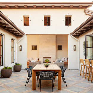 Immagine di un patio o portico mediterraneo di medie dimensioni e in cortile con un tetto a sbalzo, pavimentazioni in cemento e un caminetto