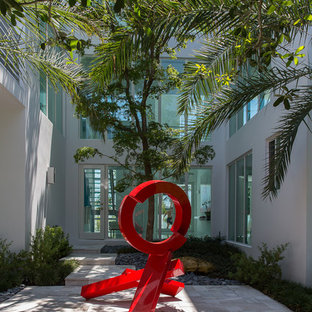 Inspiration for an expansive contemporary courtyard patio in Miami with natural stone pavers and no cover.