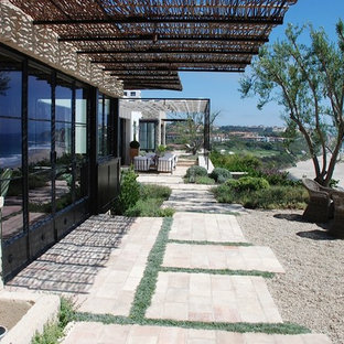 Ispirazione per un ampio patio o portico costiero dietro casa con ghiaia, un focolare e una pergola