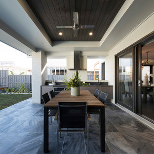 This is an example of a contemporary backyard patio in Sydney with an outdoor kitchen, tile and a roof extension.
