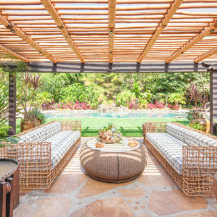 Idee per un grande patio o portico etnico dietro casa con pavimentazioni in pietra naturale e una pergola