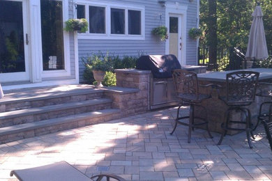 Modelo de patio clásico de tamaño medio sin cubierta en patio trasero con cocina exterior y adoquines de hormigón