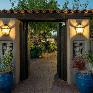 Idee per un patio o portico mediterraneo di medie dimensioni e in cortile con un giardino in vaso, pavimentazioni in mattoni e un tetto a sbalzo