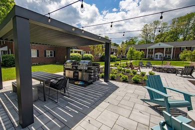 Imagen de patio minimalista de tamaño medio en patio con cocina exterior, pérgola y adoquines de hormigón