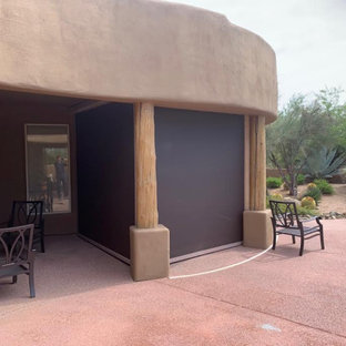 Idee per un grande patio o portico american style dietro casa con pavimentazioni in cemento e un tetto a sbalzo