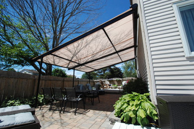 Inspiration for a large transitional backyard patio remodel in Ottawa with an awning