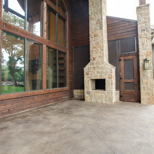 Esempio di un grande patio o portico rustico dietro casa con un focolare, lastre di cemento e un tetto a sbalzo