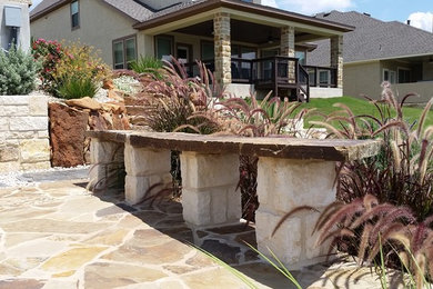 Example of a mid-sized mountain style backyard stone patio design in Austin with no cover