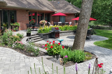 Modelo de patio tradicional renovado grande sin cubierta en patio trasero con cocina exterior y adoquines de piedra natural