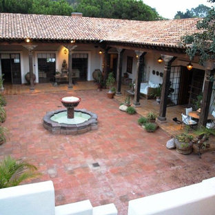 Foto di un grande patio o portico etnico in cortile con fontane, piastrelle e un tetto a sbalzo