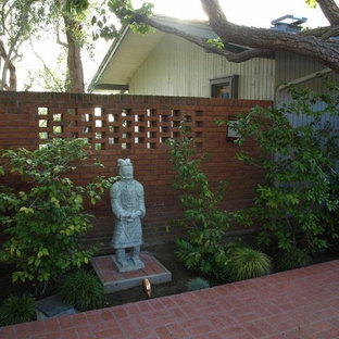 Foto di un grande patio o portico etnico dietro casa con un focolare, piastrelle e un tetto a sbalzo