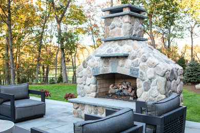 Ejemplo de patio campestre grande en patio trasero con chimenea y adoquines de piedra natural