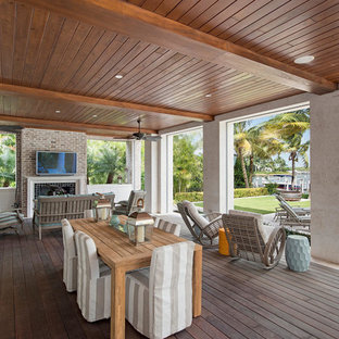 Idee per un patio o portico stile marino di medie dimensioni e dietro casa con un focolare, pedane e un tetto a sbalzo