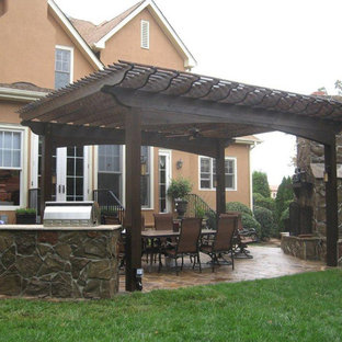 Esempio di un grande patio o portico eclettico dietro casa con un caminetto, pavimentazioni in pietra naturale e una pergola