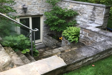 Geräumiger Patio hinter dem Haus mit Natursteinplatten in Sonstige