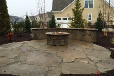 Patio - mid-sized traditional side yard stone patio idea in Other with a fire pit and no cover