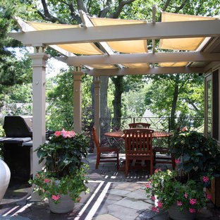 Ispirazione per un patio o portico boho chic di medie dimensioni e dietro casa con pavimentazioni in pietra naturale e un parasole