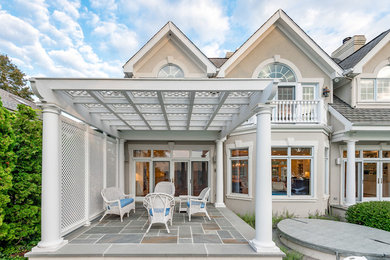 Example of a large beach style backyard tile patio design in Chicago with a pergola