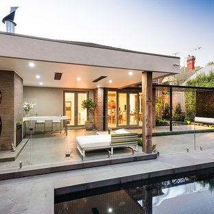 Foto di un patio o portico moderno di medie dimensioni e dietro casa con un focolare, pavimentazioni in cemento e un tetto a sbalzo