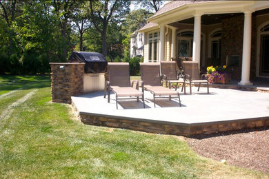 Imagen de patio clásico de tamaño medio sin cubierta en patio trasero con brasero y adoquines de hormigón