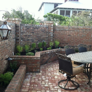Ispirazione per un patio o portico chic di medie dimensioni con pavimentazioni in mattoni e nessuna copertura