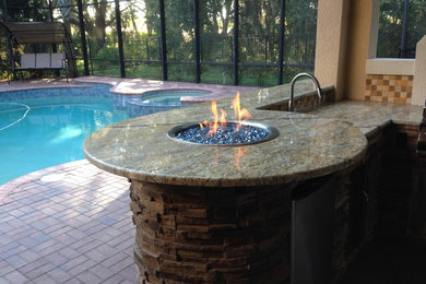 Example of a mid-sized classic backyard stamped concrete patio kitchen design in Tampa with a pergola