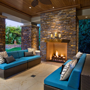 Foto di un grande patio o portico contemporaneo dietro casa con un focolare, un tetto a sbalzo e pavimentazioni in pietra naturale