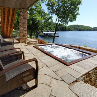 Esempio di un grande patio o portico stile americano dietro casa con pavimentazioni in cemento, un focolare e un tetto a sbalzo