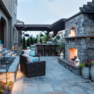 Immagine di un patio o portico minimal di medie dimensioni e dietro casa con un focolare, pavimentazioni in pietra naturale e una pergola