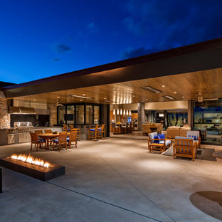 Ispirazione per un grande patio o portico american style dietro casa con un focolare, lastre di cemento e un tetto a sbalzo