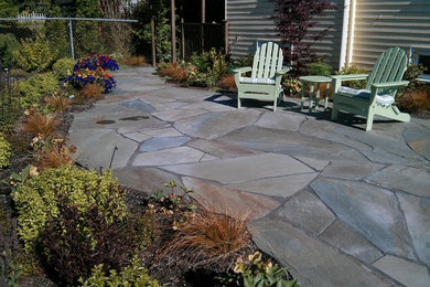 Medium sized beach style back patio in Seattle with natural stone paving and no cover.