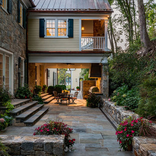Immagine di un patio o portico country di medie dimensioni e nel cortile laterale con pavimentazioni in pietra naturale e un tetto a sbalzo