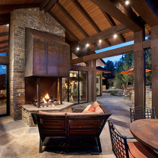 Idee per un patio o portico rustico di medie dimensioni e dietro casa con un focolare, pavimentazioni in pietra naturale e un tetto a sbalzo