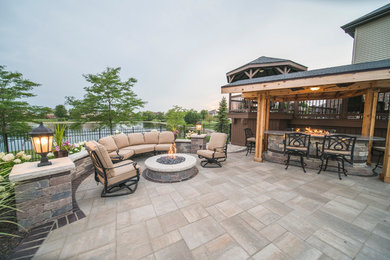 Example of a large trendy backyard stone patio design in Chicago with a fire pit and a pergola