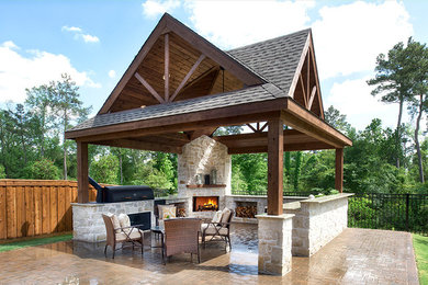 Modelo de patio rústico grande en patio trasero con cocina exterior, adoquines de hormigón y cenador