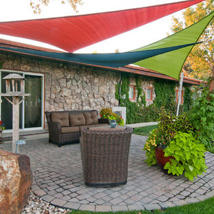 Esempio di un patio o portico bohémian dietro casa con un giardino in vaso, pavimentazioni in cemento e un parasole