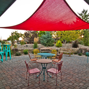 Idee per un patio o portico boho chic dietro casa con un focolare, pavimentazioni in cemento e un parasole