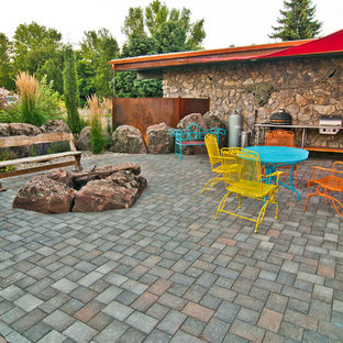 Ispirazione per un patio o portico boho chic dietro casa con un focolare, pavimentazioni in cemento e un parasole