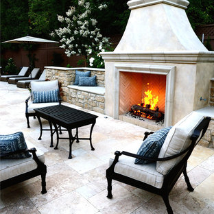 Esempio di un grande patio o portico chic dietro casa con pavimentazioni in pietra naturale e un caminetto