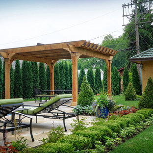 Foto di un patio o portico vittoriano di medie dimensioni e dietro casa con un giardino in vaso, pavimentazioni in pietra naturale e una pergola