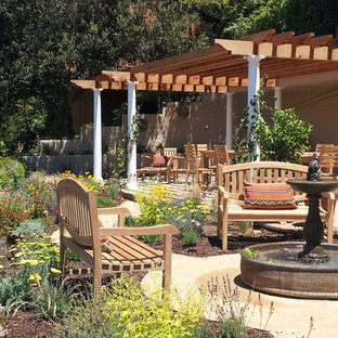 Idee per un grande patio o portico mediterraneo dietro casa con fontane, graniglia di granito e una pergola