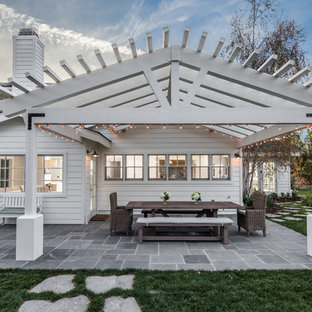 Foto di un patio o portico country di medie dimensioni e dietro casa con pavimentazioni in pietra naturale e una pergola