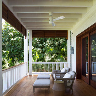 Immagine di un grande patio o portico tropicale dietro casa con pedane e un tetto a sbalzo