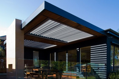 Diseño de patio moderno grande en patio trasero con cocina exterior, entablado y toldo