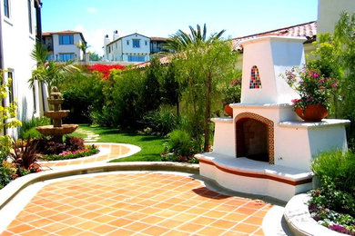 オレンジカウンティにある広い地中海スタイルのおしゃれな裏庭のテラス (コンクリート敷き	、屋外暖炉) の写真