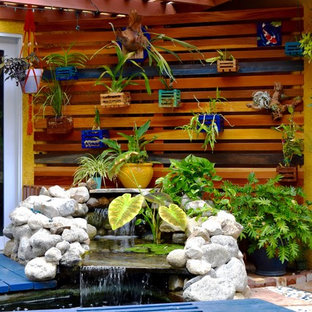 Esempio di un patio o portico tropicale di medie dimensioni e dietro casa con pedane e un gazebo o capanno
