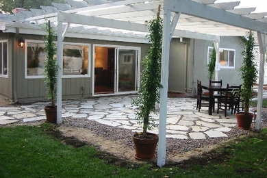 Ejemplo de patio clásico de tamaño medio en patio trasero con adoquines de piedra natural y pérgola
