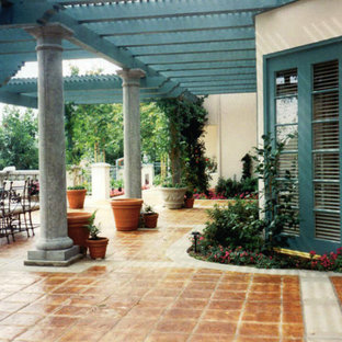 Ispirazione per un patio o portico mediterraneo di medie dimensioni e dietro casa con un caminetto, cemento stampato e un gazebo o capanno