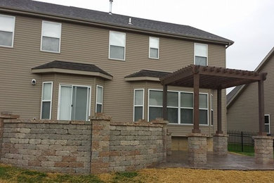 Example of a mid-sized backyard stamped concrete patio design in St Louis with a fire pit and a pergola