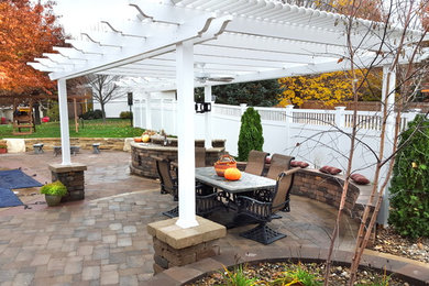 Mid-sized transitional backyard concrete paver patio photo in Other with a pergola